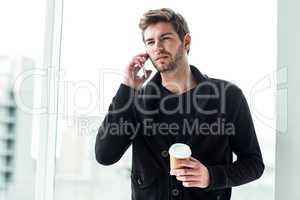 Handsome man on phone call holding disposable cup