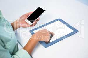 Businesswoman using her digital tablet and her smartphone