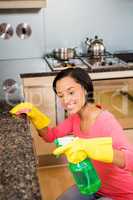 Smiling brunette cleaning kitchen counter