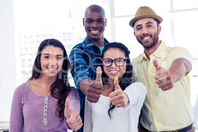 Portrait of creative business people showing thumbs up