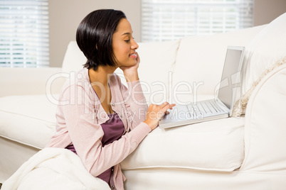 Smiling brunette using laptop