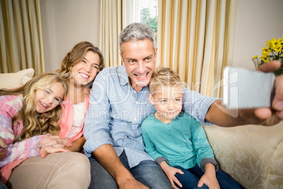 Happy family taking selfie on the sofa