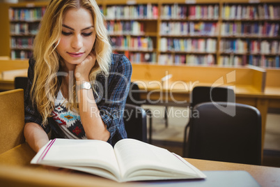 Smiling student reading a book at table