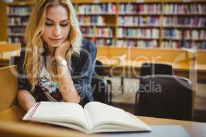 Smiling student reading a book at table