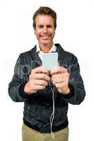 Portrait of happy man listening music while using mobile phone