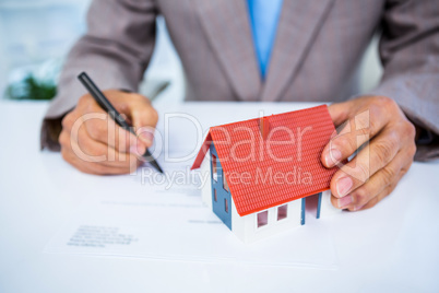 Businessman taking notes with miniature house