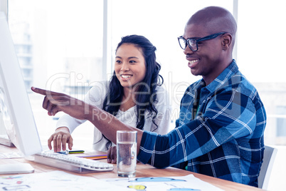 Cheerful businessman discussing with businesswoman over computer