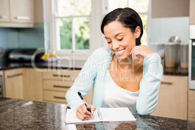 Smiling brunette writing on note pad