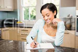 Smiling brunette writing on note pad
