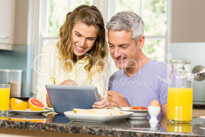 Happy couple using tablet and having breakfast Happy couple using tablet and having breakfast