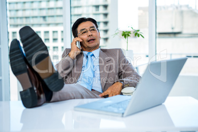 Businessman on the phone with his feet on his desk
