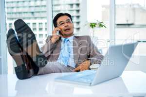 Businessman on the phone with his feet on his desk