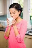 Peaceful brunette holding white cup