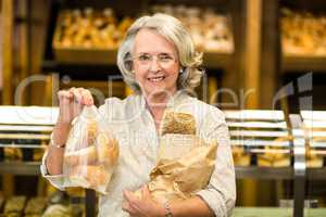 Smiling senior woman holding bags with bread