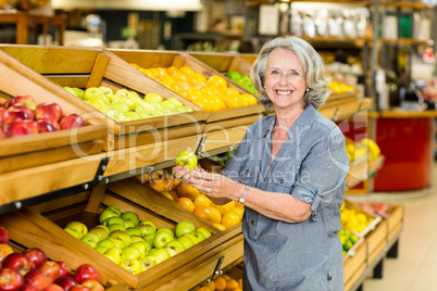Smiling senior woman picking apple
