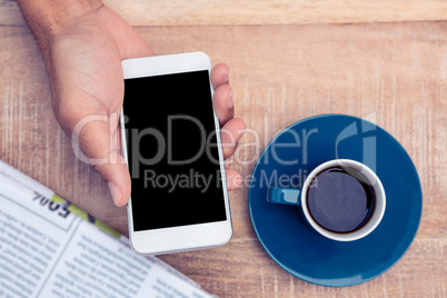 Person using smart phone by coffee and document on table