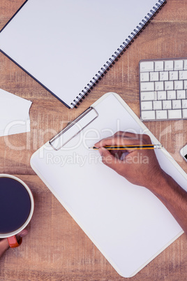 Businessman writing on notebook by coffee
