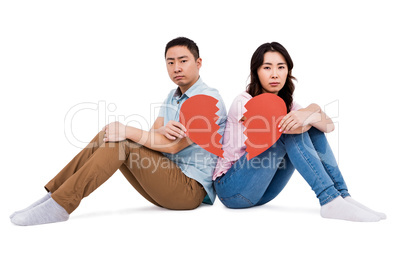 Portrait of sad couple holding broken heart pieces