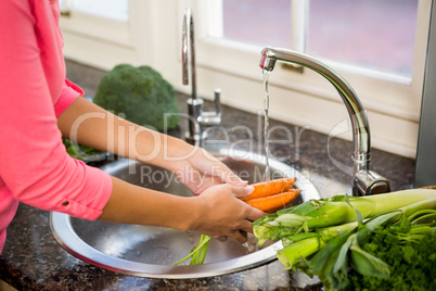 Mid section of woman washing carrots