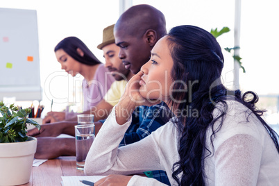 Thoughtful business woman sitting with colleagues