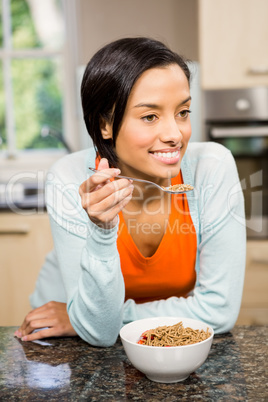 Smiling brunette eating cereals
