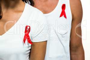 Midsection of people with red ribbon on clothes