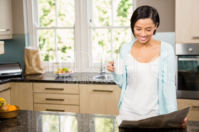 Smiling brunette reading newspaper and holding cup