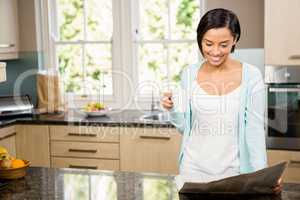 Smiling brunette reading newspaper and holding cup