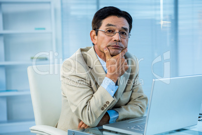 Thoughtful asian businessman looking at the camera