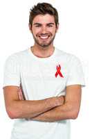 Smiling man with arms crossed with red ribbon