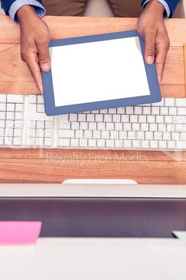 Businessman holding digital tablet by keyboard at desk