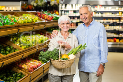 Smiling senior couple holding basket with vegetables