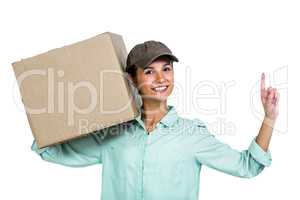 Smiling delivery woman holding box pointing up