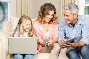Happy family using laptop, tablet and smartphone