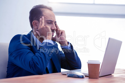 Tensed businessman working on laptop