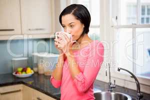 Standing brunette drinking by cup