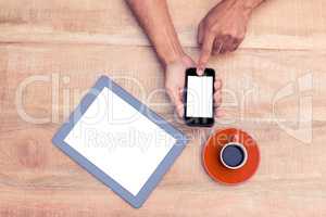 Person using smart phone by coffee and tablet on table