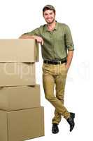 Handsome postman standing by cardboard boxes