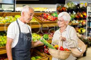 Senior customer and worker discussing vegetables