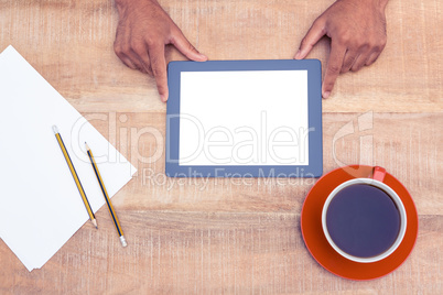 Man with digital tablet over table by coffee and papers