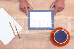 Man with digital tablet over table by coffee and papers