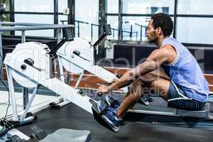 Muscular man using rowing machine