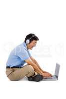 Side view of cheerful man listening music while using laptop