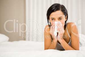 Brunette sneezing on bed