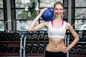 Fit woman with hand on hip holding medicine ball
