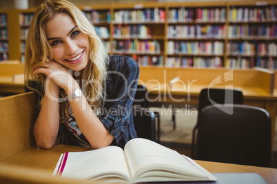 Smiling student reading a book at table