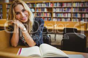 Smiling student reading a book at table