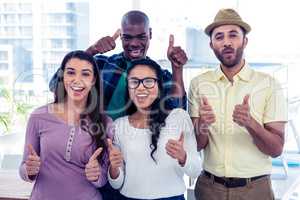 Portrait of creative business people with thumbs up
