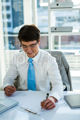 Smiling asian businessman writing a report