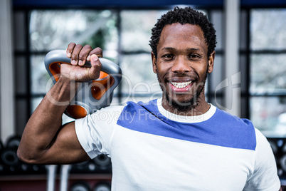 Smiling muscular man lifting kettlebells